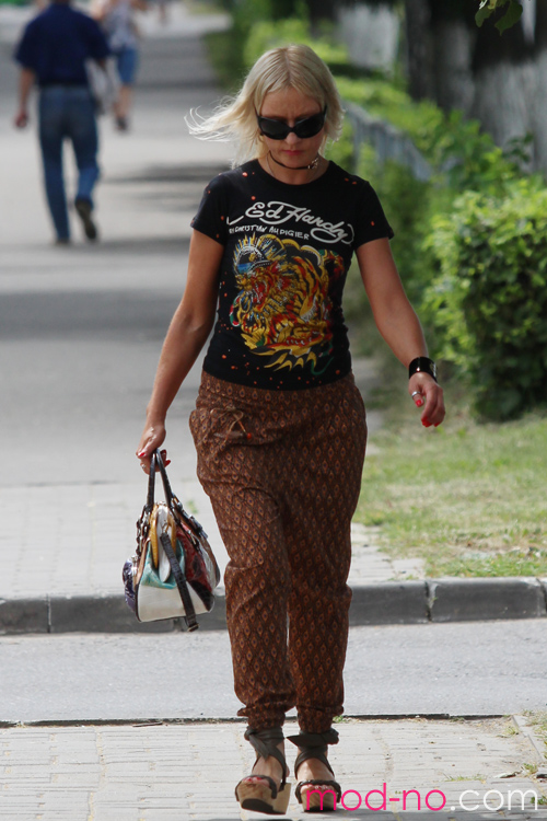 Moda uliczna w Saligorsku. 06/2013 (ubrania i obraz: top z nadrukiem czarny, spodnie brązowe, sandały na koturnie, torebka wielokolorowa)
