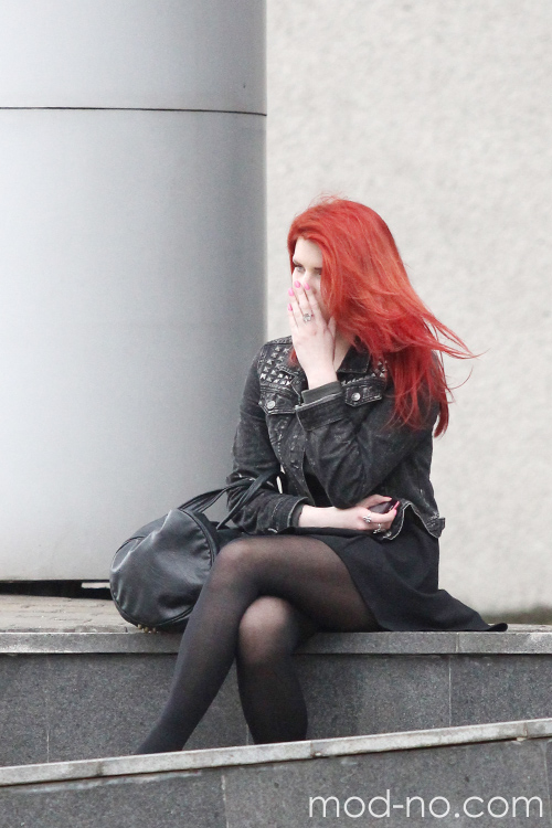 Moda uliczna w Mińsku. Czerwiec 2014 (ubrania i obraz: rajstopy czarne, torebka czarna, spódnica czarna, kurtka czarna, rude włosy)